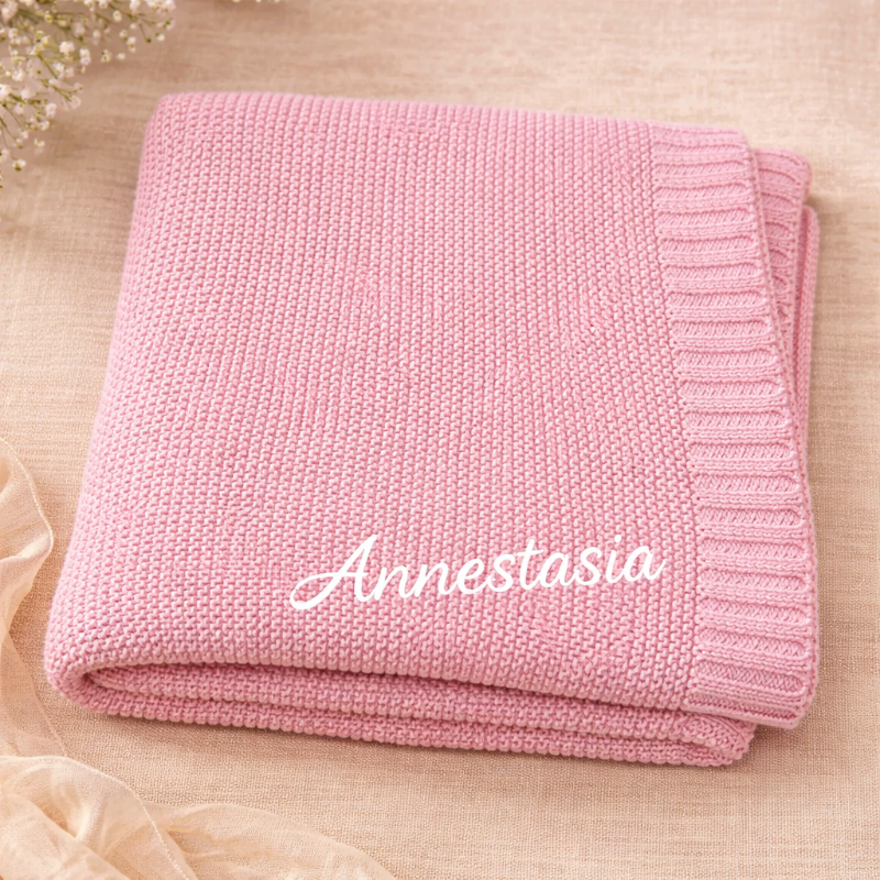 Rosa gestrickte Babydecke mit einem Namen in weißen Buchstaben