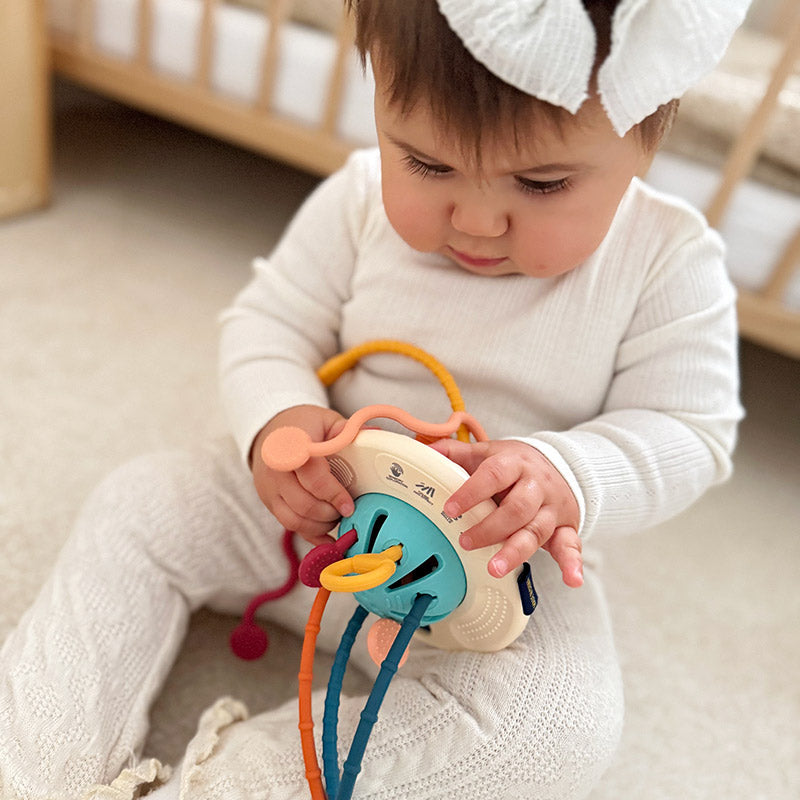 Baby spielt sitzend mit dem Greifling aus Silikon