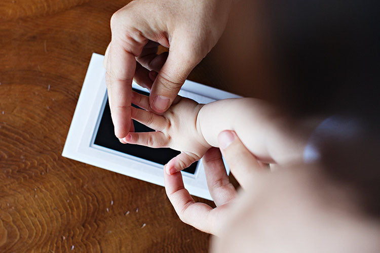 Elternteil macht mit dem Abdruckset einen Fußabdruck des Babys