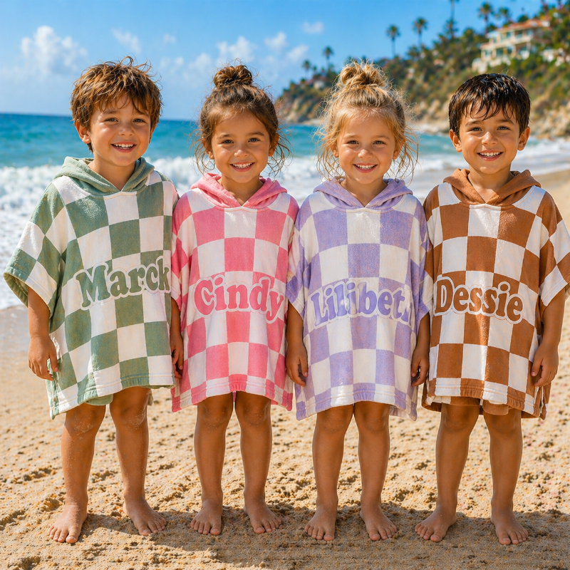 Vier Kinder am Strand in ihrem Kapuzenhandtuch mit Namen
