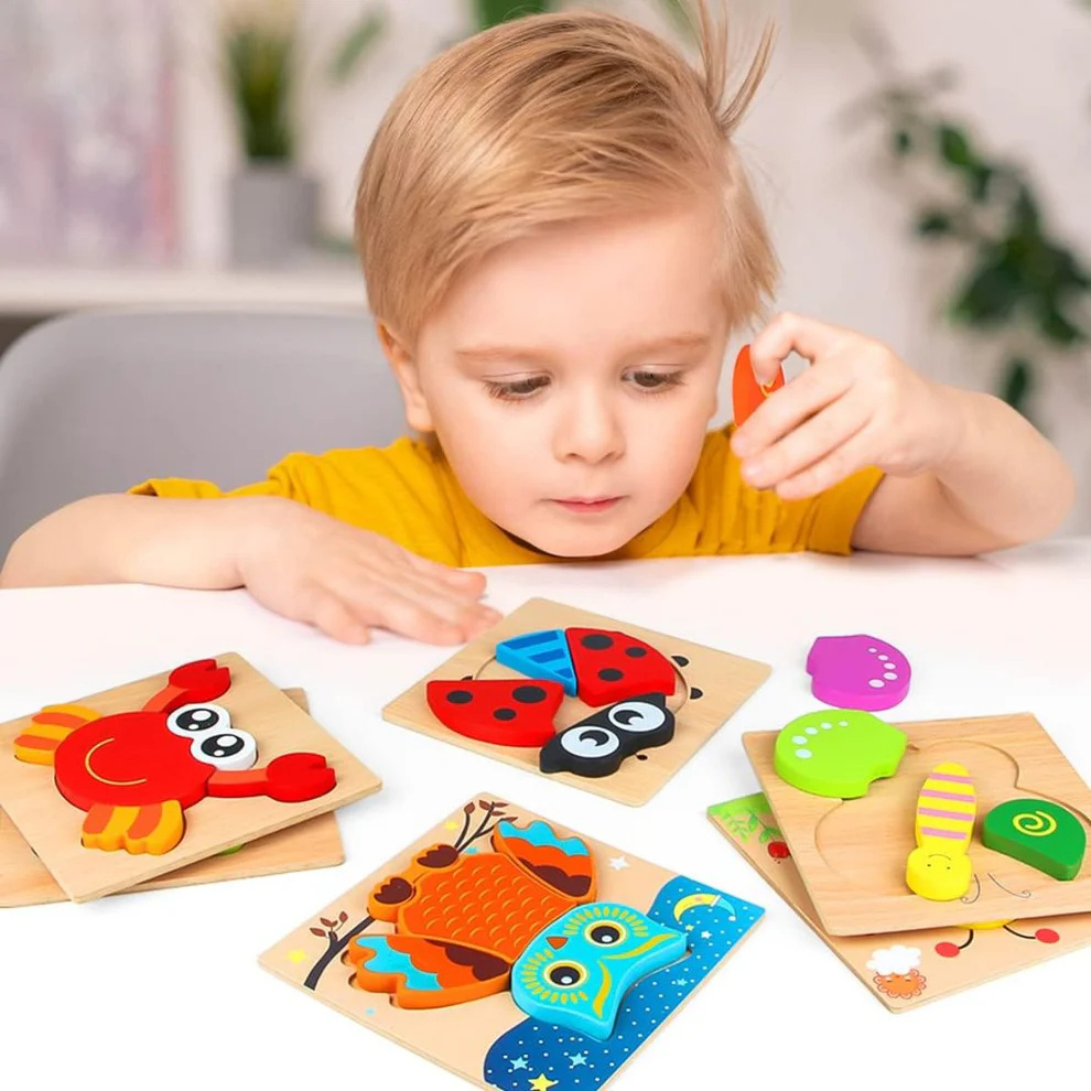 Junge legt die Tierpuzzles aus Holz am Tisch