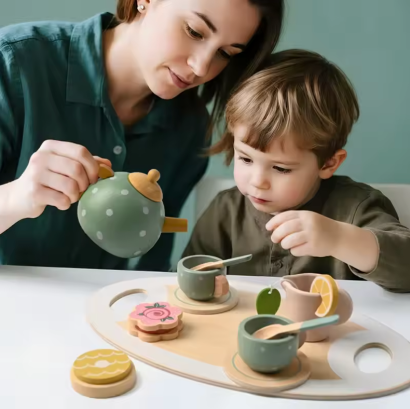Mutter und Kind spielen gemeinsam Teerunde am Tisch