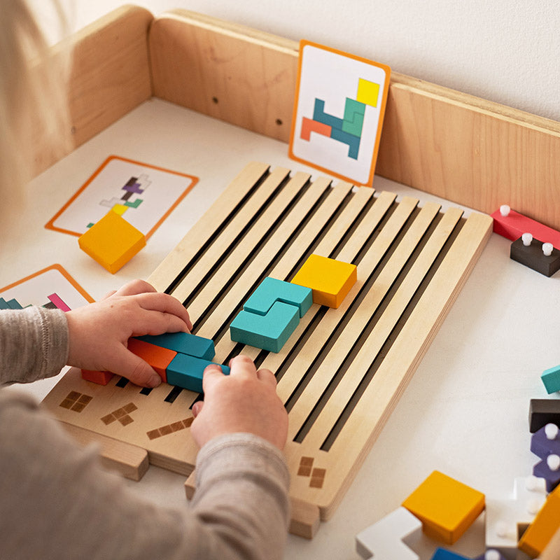 Kind spielt mit dem Holzpuzzle und einer Aufgabenkarte daneben