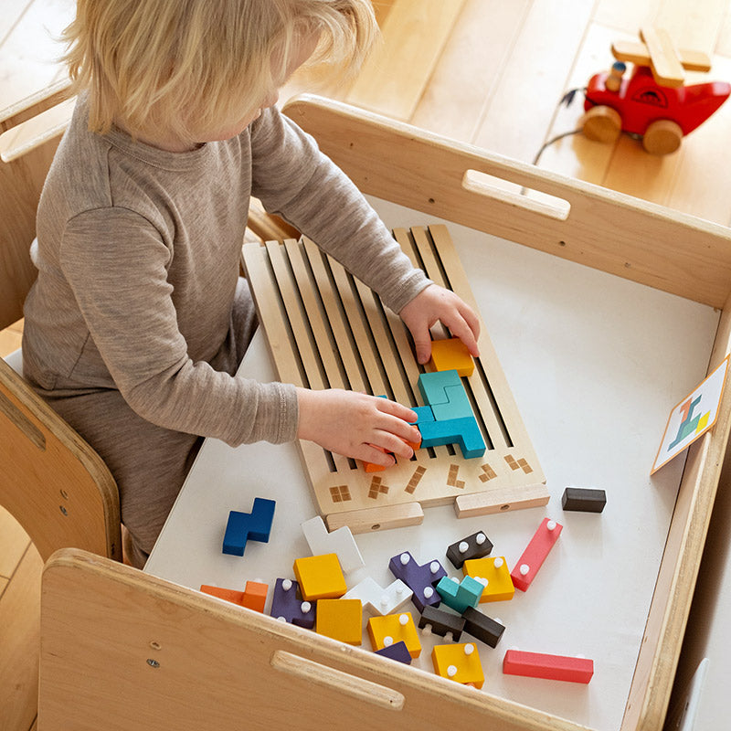 Kind legt bunte Klötze in das Holzpuzzle-Brett
