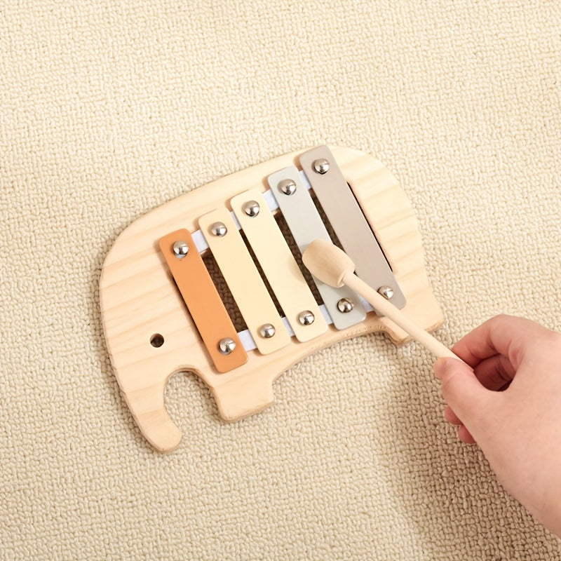 Kinderhand schlägt mit dem Schlägel auf das Xylophon aus Holz in Elefantenform